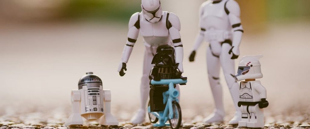 Deux figurines Stormtrooper s'occupant et faisant faire du vélo à des figurines Lego StarWars R2D2, Dark Vador et Clone.